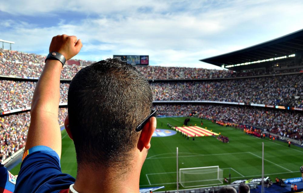 Soccer fan cheering while watching match in packed stadium