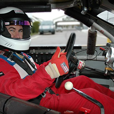 Race car driver sitting in a seat giving a thumbs up